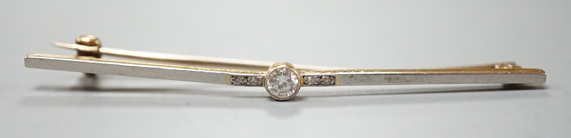 An Edwardian 15ct and single stone diamond set bar brooch, with diamond chip setting, 57mm, gross weight 3.1 grams.